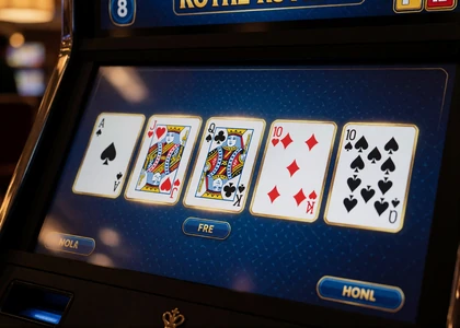 Video-Poker-Bildschirm mit f&uuml;nf offenen Spielkarten und goldenen Rahmen im dunklen Casino-Automaten